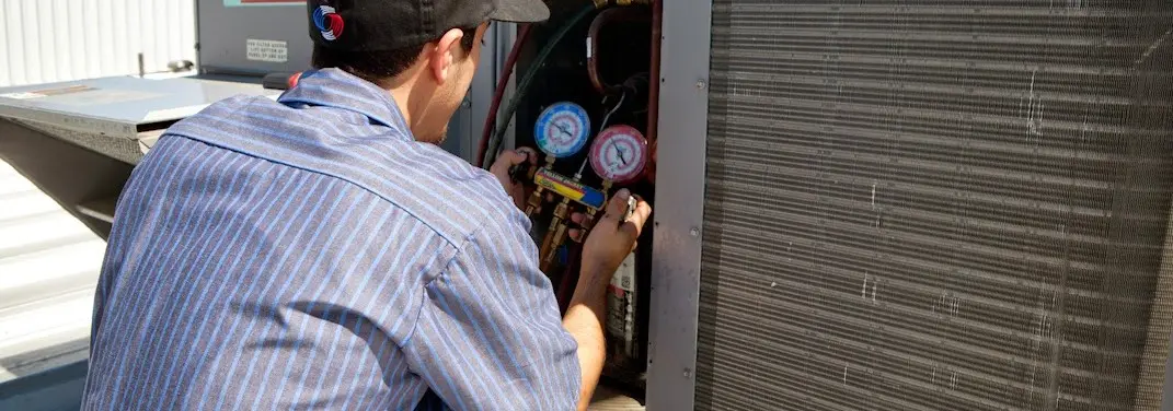 HVAC technician servicing a condenser unit in Thompson
