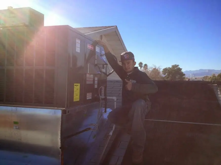 HVAC technician performing Air Duct Cleaning on a rooftop unit in Thompson